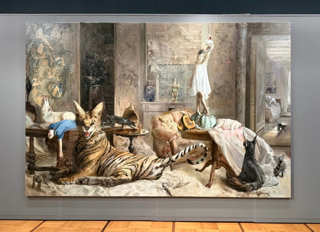 Голяма сюрреалистична картина от изложбата на Гийермо Лорка, изобразяваща интериор с момиче в бяла рокля, тигър, котки и други животни в мистична сцена.
