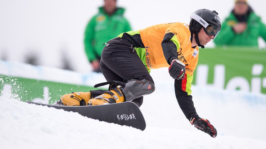 Радослав Янков по време на състезание по алпийски сноуборд, в динамичен завой по заснежената писта.